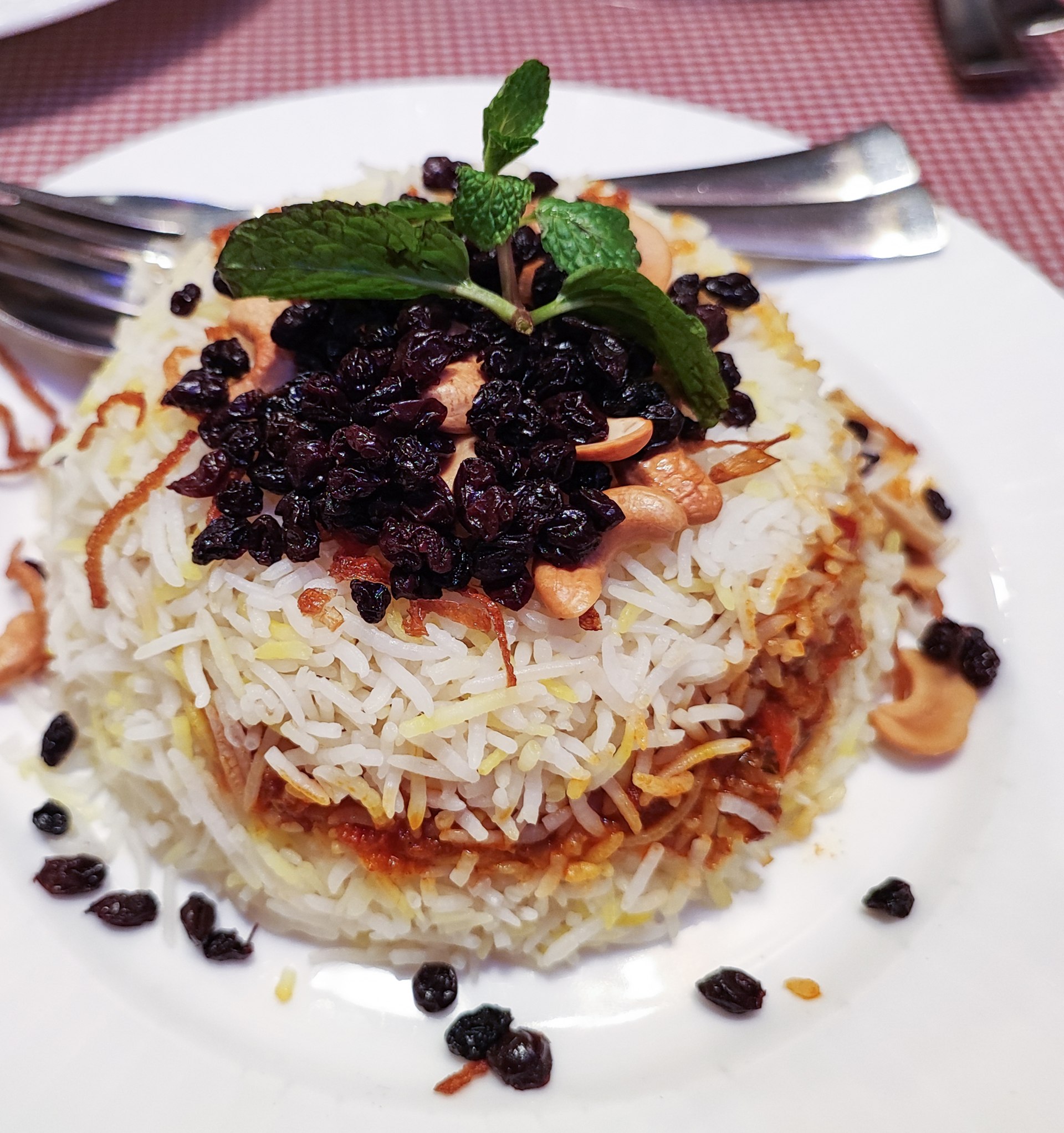 Parsi mutton berry pulao topped with barberries, cashews, fried onions and mint